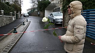 A youth holds a white rose at the entrance of a private Catholic school after a teacher of Spanish has been stabbed to death by a high school student, Wednesday, Feb. 22, 2023