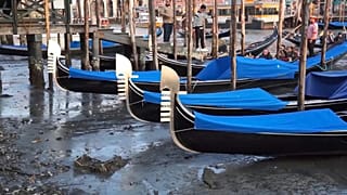 Venetian gondolas beached on the side of a canal