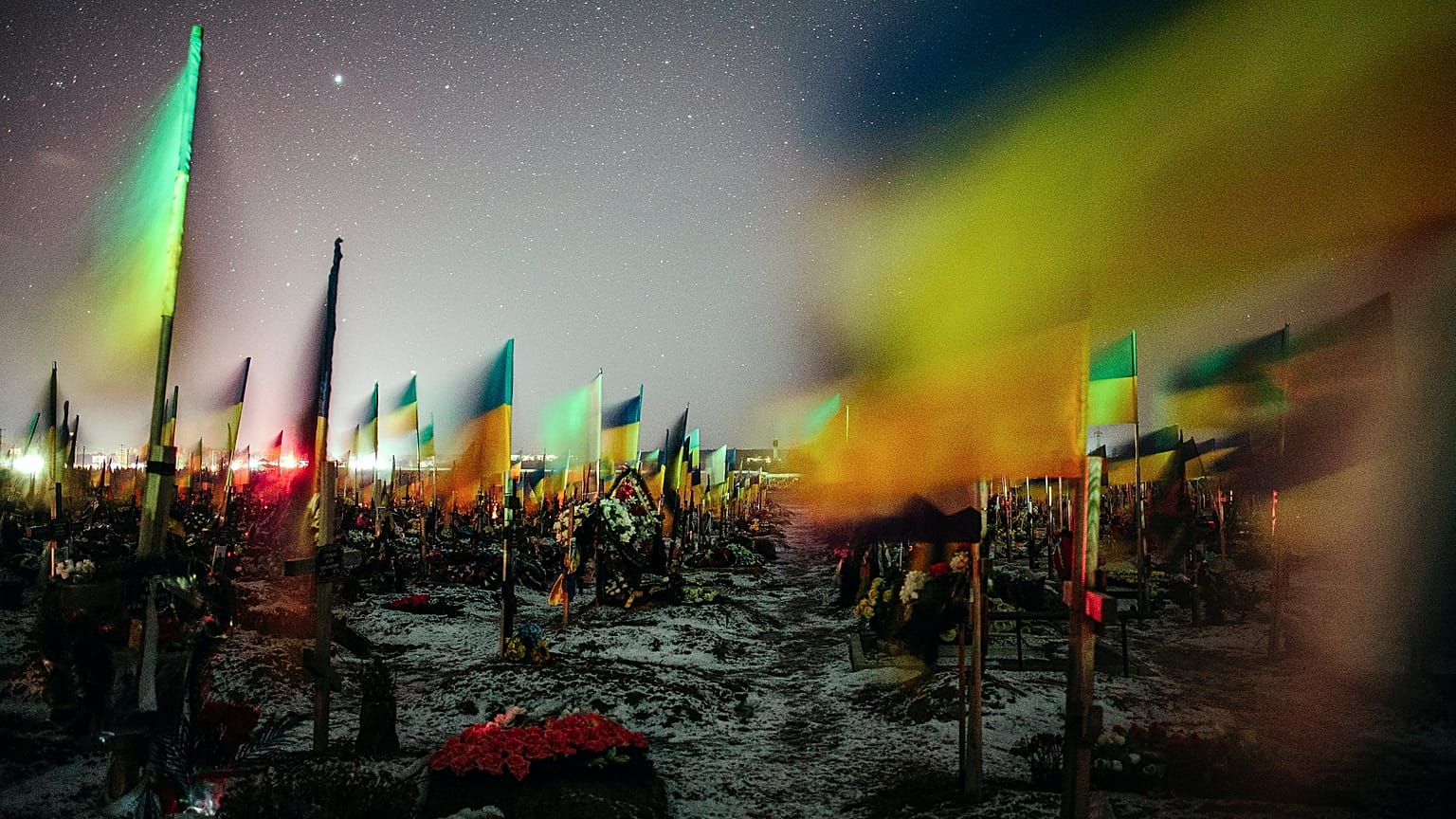 2023. február 23-án közreadott, hosszú expozíciós idővel készített kép ukrán zászlókról a harkivi katonai temetőben február 22-én éjjel.