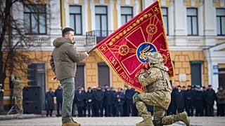 Президент Украины Владимир Зеленский c флагом воинской части в ходе церемонии в Киеве 24 фквраля 2023 г.