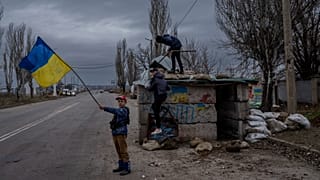 Niños ucranianos juegan en un puesto de control abandonado en Jersón, en el sur de Ucrania, el 23 de noviembre de 2022.