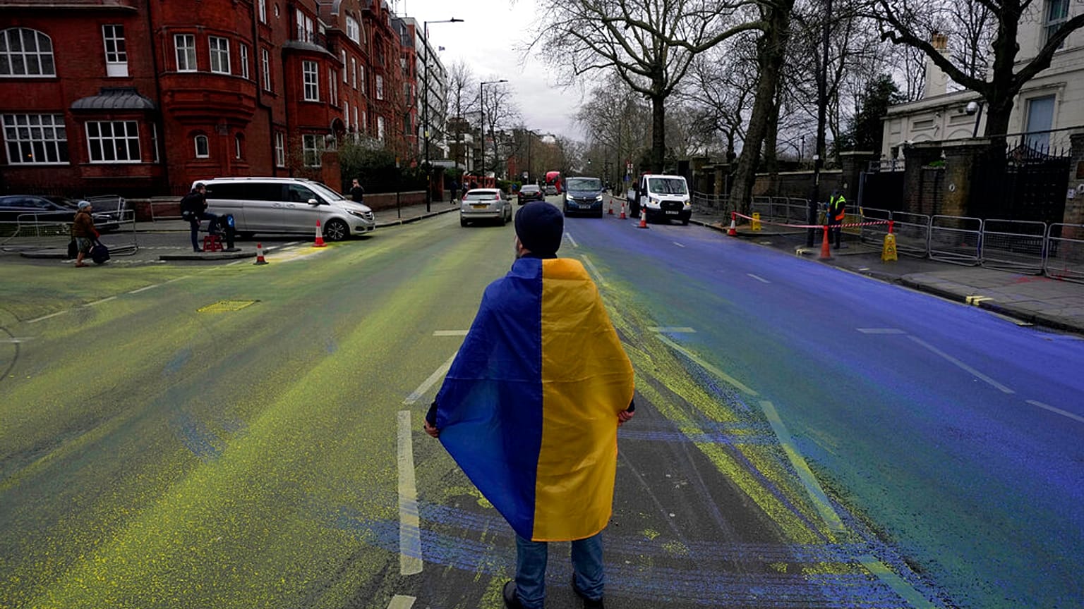 Протестующий c флагом  Украины на проезжей части, разрисованной в цвета краинского флага