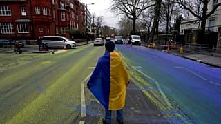 Протестующий c флагом  Украины на проезжей части, разрисованной в цвета краинского флага