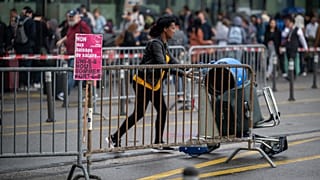 Un viajero empuja un carrito con equipaje junto a una pancarta sindical en la que se lee "no a la pérdida salarial, unidos somos más fuertes" en el Aeropuerto Internacional de Ginebra. 