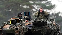 German Defense Minister Boris Pistorius, right, sits on a Leopard 2 tank