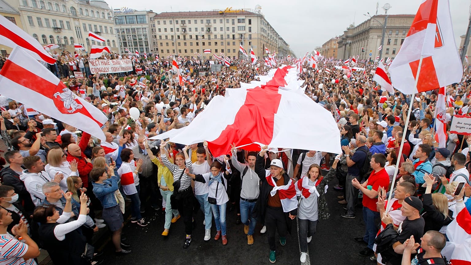 Demonstrators carry a huge historical flag of Belarus as thousands gather for a protest at the Independence square in Minsk, Belarus.