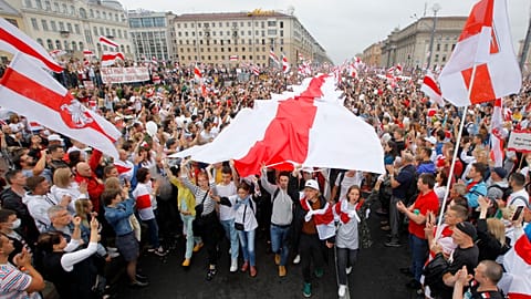 Demonstrators carry a huge historical flag of Belarus as thousands gather for a protest at the Independence square in Minsk, Belarus.