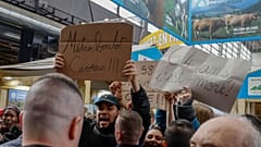 فرنسيون يحملون لافتات كتب عليها "مترو، عمل، قبر" أثناء احتجاجهم ضد رفع الحد الأدنى لسن التقاعد خلال زيارة ماكرون لمعرض باريس للفلاحة. 2023/02/25