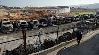 فلسطيني بالقرب من سيارات أحرقها مستوطنون في الضفة الغربية الأحد