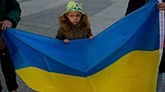 Un niño ucraniano cerca de la bandera de Ucrania mientras participa en una protesta por el primer aniversario de la invasión rusa de Ucrania, en Pamplona, norte de España.