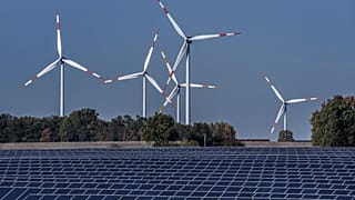 Wind turbines turn behind a solar farm in Rapshagen, Germany, Oct. 28, 2021.
