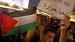 متظاهر إسرائيلي يرفع ورقة كتب عليها "تحيا حوارة" 
