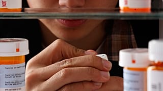 Photo illustration of teenager looking through medication in home cabinet, March 11, 2010.