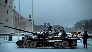 A woman plays with a dog on the destroyed Russian tank t Cathedral Square in Vilnius, Lithuania, Friday, Feb. 24, 2023.