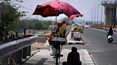 A snacks vendor sits under a shade and waits for customer on a hot summer afternoon in Jammu, India, May 19, 2022. 