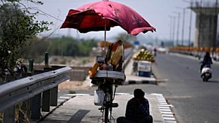 A snacks vendor sits under a shade and waits for customer on a hot summer afternoon in Jammu, India, May 19, 2022. 