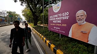 Commuters walk past a banner with Indian Prime Minister's Narendra Modi photograph welcoming delegates of G20 foreign ministers meeting, in New Delhi, India, March 1, 2023. 