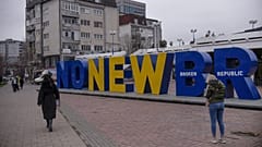 Kosovan Albanians walk past the newborn monument changed to "No New Broken Republic" in Pristina on February 27, 2023.