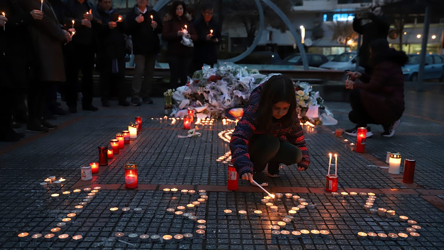 Una niña enciende una vela, en memoria de las víctimas de la colisión de trenes, frente a la estación de tren de Larissa, al norte de Atenas, Grecia, el 2 de marzo de 2023. 