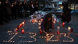 Una niña enciende una vela, en memoria de las víctimas de la colisión de trenes, frente a la estación de tren de Larissa, al norte de Atenas, Grecia, el 2 de marzo de 2023.