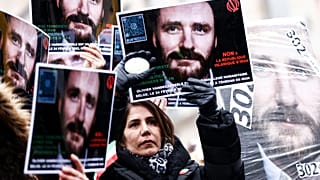 Demonstrators hold placards with the portrait of detained Belgian aid worker Olivier Vandecasteele, as they take part in a solidarity rally in Brussels on January 22, 2023.