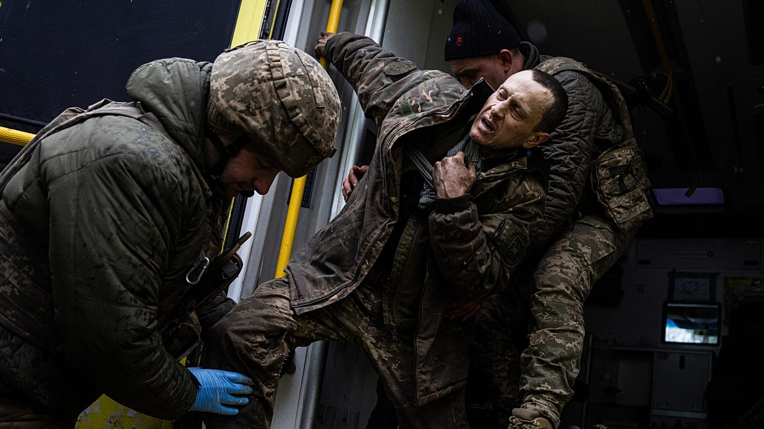 Ukrainian military medics help their wounded comrade to get out from an ambulance after arriving from the battlefield to the field hospital near Bakhmut