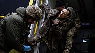 Ukrainian military medics help their wounded comrade to get out from an ambulance after arriving from the battlefield to the field hospital near Bakhmut