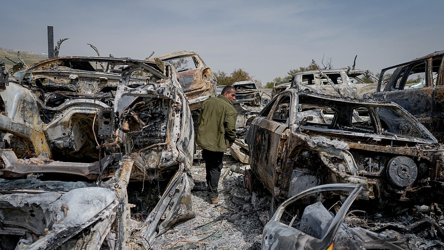 A Palestinian man walks between scorched cars in a scrapyard, in Hawara, near Nablus, West Bank