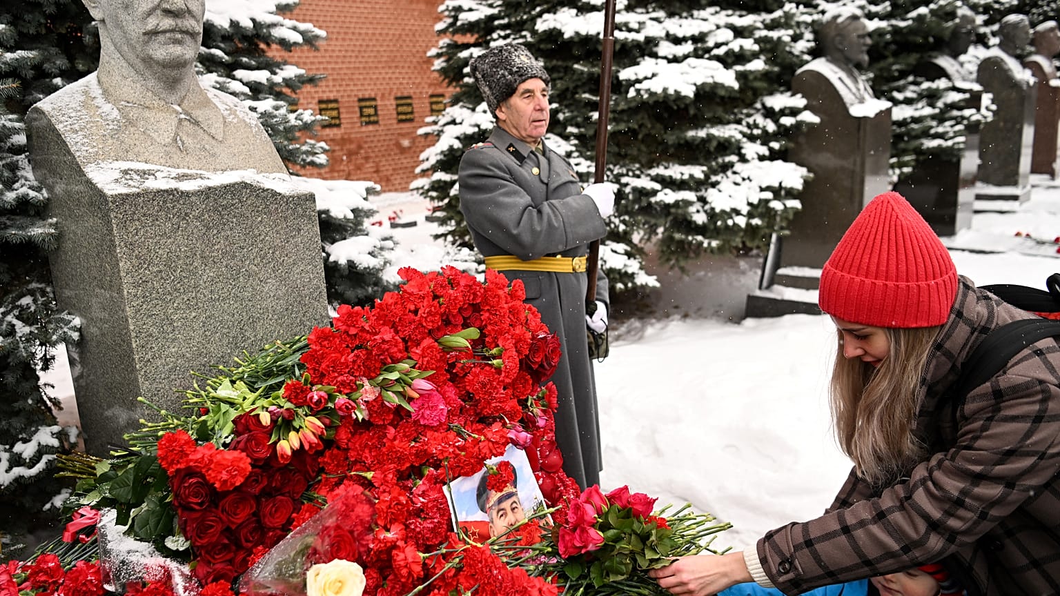 Eine Frau legt Blumen an der Stalin-Büste nieder
