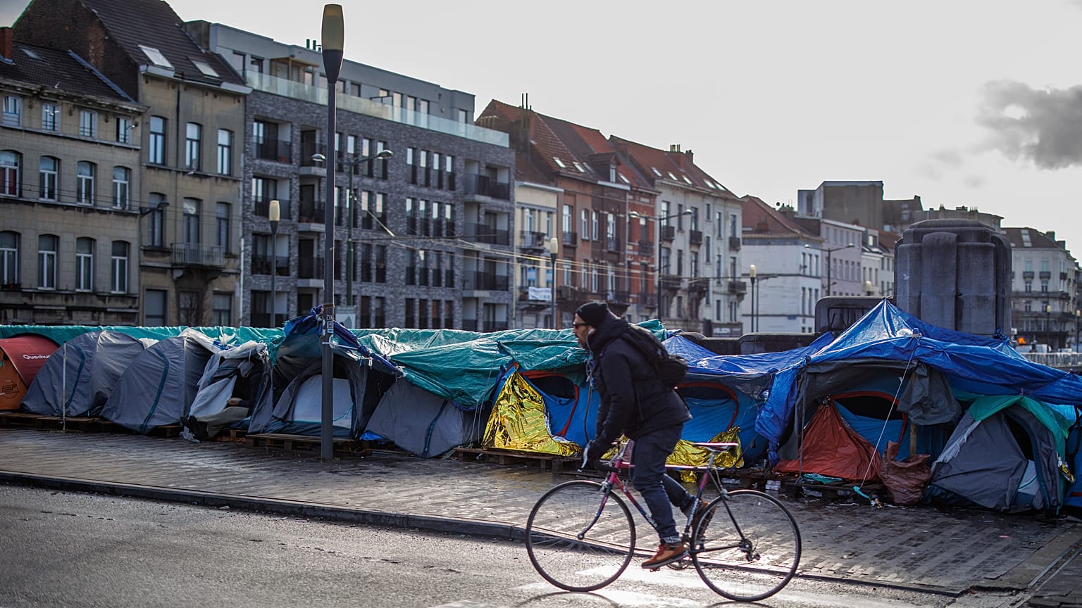 Ein Mann fährt mit seinem Fahrrad an einem behelfsmäßigen Zeltlager vor dem Petit Chateau-Aufnahmezentrum in Brüssel vorbei, 17. Januar 2023. 