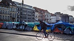 Ein Mann fährt mit seinem Fahrrad an einem behelfsmäßigen Zeltlager vor dem Petit Chateau-Aufnahmezentrum in Brüssel vorbei, 17. Januar 2023. 