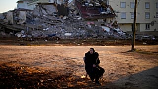 A woman sits on a chair as she waits for her belongings to take away from a damaged building in Pazarcik, Turkey, Monday, Feb. 13, 2023.