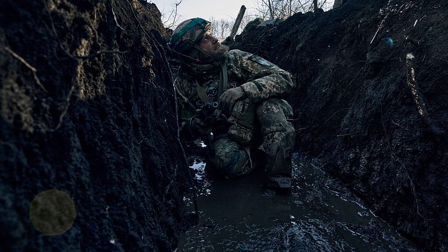 A Ukrainian soldier takes cover in a trench under Russian shelling on the frontline close to Bakhmut, Donetsk region, Ukraine, Sunday, March 5, 2023.