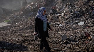 Egy nő sétál Antakya utcáin a földrengést követően