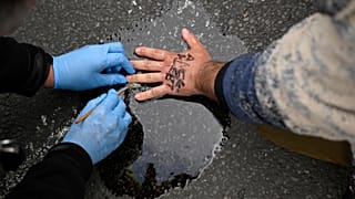 A policeman works on the hand of a man who has glued himself on the street in Berlin.