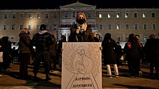 Женщина с плакатом перед греческим парламентом в Афинах во время демонстрации протеста в связи с железнодорожной катастрофой у Темпе. 3 марта 2023 года