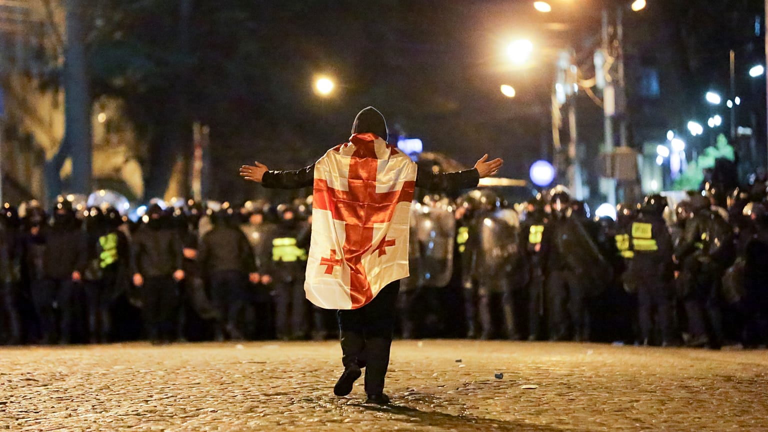 Un manifestante con una bandera nacional georgiana camina hacia la línea policial frente al edificio del Parlamento en Tiflis, Georgia, el martes 7 de marzo de 2023.