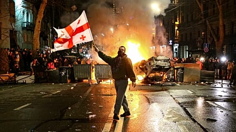 Un homme manifeste en brandissant un drapeau de la Géorgie.