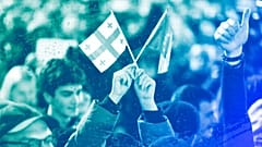 A young woman holds a Georgian national flag and an EU flag during a protest near the Georgian parliament building in Tbilisi, 9 March 2023