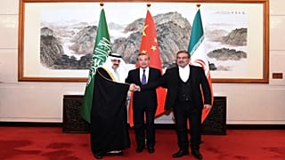 أمين المجلس الأعلى للأمن القومي الإيراني علي شمخاني (يمين) يصافح مستشار الأمن القومي السعودي مسعد بن محمد العيبان بوساطة صينية