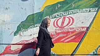 سيدة إيرانية تسير أمام جدارية لعلم إيران في أحد شوارع العاصمة طهران 19/09/2019