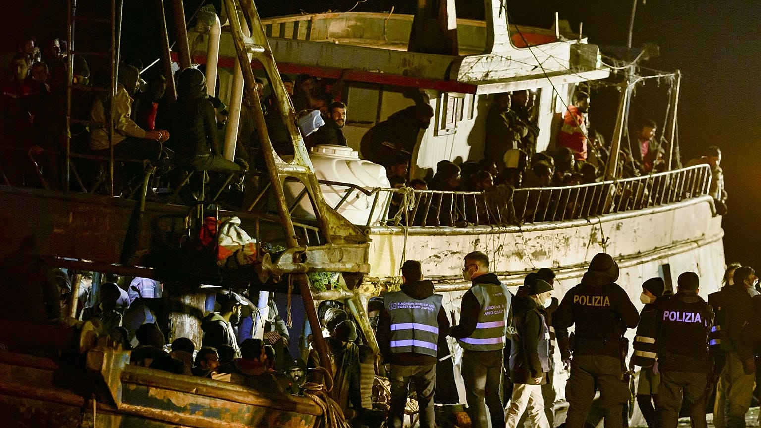 Police check a fishing boat with some 500 migrants in the southern Italian port of Crotone, early March 11, 2023. 