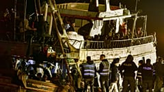 Police check a fishing boat with some 500 migrants in the southern Italian port of Crotone, early March 11, 2023. 