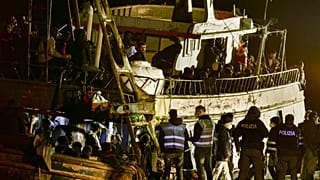 Police check a fishing boat with some 500 migrants in the southern Italian port of Crotone, early March 11, 2023. 