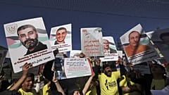 أشخاص يحملون لافتات عليها صور فلسطينيين محتجزين في السجون الإسرائيلية خلال "ماراثون حرية الحركة في فلسطين" في بيت لحم بالضفة الغربية المحتلة، 10 مارس 2023.