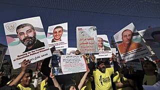 أشخاص يحملون لافتات عليها صور فلسطينيين محتجزين في السجون الإسرائيلية خلال "ماراثون حرية الحركة في فلسطين" في بيت لحم بالضفة الغربية المحتلة، 10 مارس 2023.