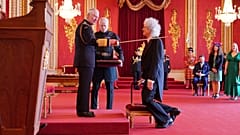 A pillanat, amikor a király lovaggá üti a Queen együttes gitárosát, Brian Mayt
