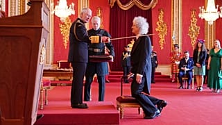 A pillanat, amikor a király lovaggá üti a Queen együttes gitárosát, Brian Mayt