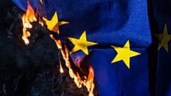 An EU flag burns. 