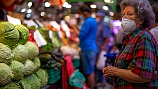 Un cliente con mascarilla espera para comprar verduras en el mercado Maravillas de Madrid.
